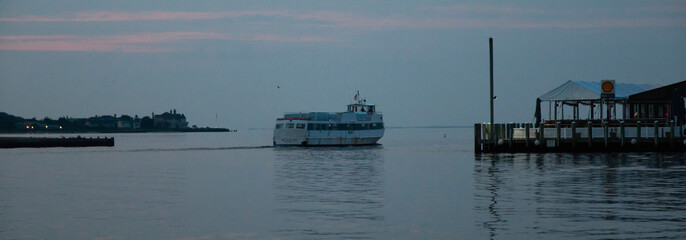 Early Morning Fire Island Ferry moving Across Calm Water Near Coastal Town
