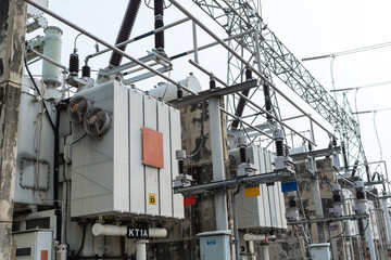 High voltage power transformers with cooling fans installed in electrical substation, essential equipment for voltage conversion, energy transmission, and reliable electricity distribution system.
