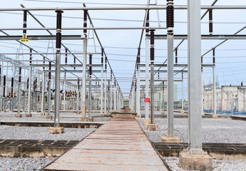 High voltage electrical substation with metal structures, insulators, and power lines. Industrial...