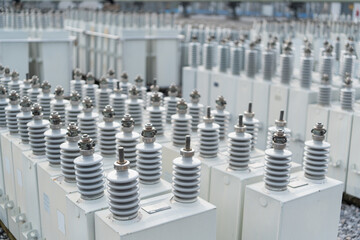 Obraz premium Large installation of capacitor banks with multiple ceramic insulators in electrical substation, used for energy storage, reactive power compensation, and efficient electricity distribution.