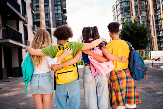 Group of diverse students embracing together outdoors in a modern city environment during daylight in casual attire
