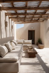 A serene outdoor seating area under a wooden pergola, bathed in soft sunlight.  The neutral tones and natural textures create a tranquil and inviting atmosphere.