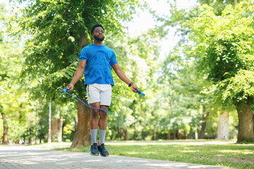 Young man jumping rope in park, exercising outdoors on a sunny day.

