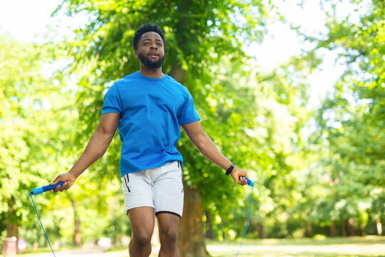 African american man training with jump rope outdoors in park.