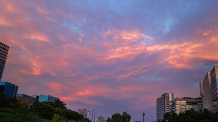 A dramatic sunset sky with textured clouds in a variety of hues. Warm, vivid oranges and reds blend together to create a complex natural canvas.