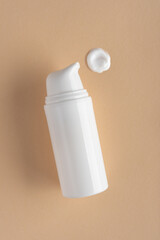 Minimal Skincare Tubes with Face Cream Drops on Beige Background