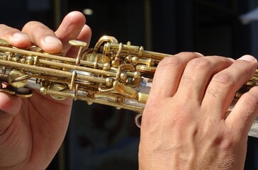 Musician's hands playing soprano saxophone with skill