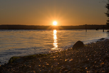 The sun rises from behind the hills. Sunrise on the lake shore.