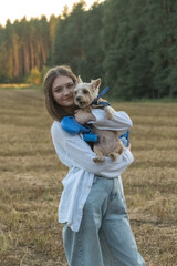 Portrait of a young beautiful long-haired girl with a Yorkshire Terrier outdoors.