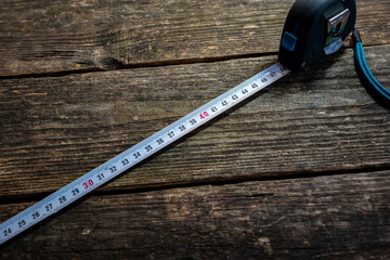 Tape measurer on aged weathered pine wood boards, space for text.