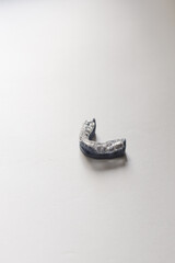 Transparent orthodontic retainer on a white minimal surface. Dental prosthetic tool for teeth alignment and oral care. High-quality studio shot.