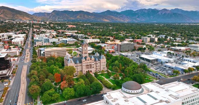 Gorgeous view of Salt Lake City and County Building surrounded by the green park. Aerial perspective on the city scenery outlined by the mountain range.