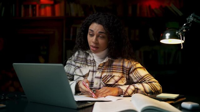 Young Black woman conducting evening online lesson on laptop, virtual education