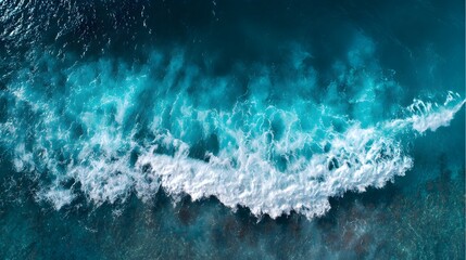 Fototapeta premium Aerial view of ocean waves crashing on the shore, showcasing vibrant turquoise and white foam