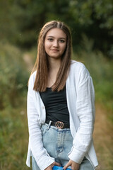Obraz premium Portrait of a young beautiful long-haired girl in a black T-shirt outdoors.