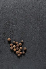 Black peppercorns and ground pepper on dark background