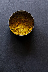 Golden Curry Powder in Metal Tin on Dark Slate Background