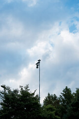 Street Light Tower Against Cloudy Sky – Urban and Natural Contrast