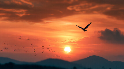 Fototapeta premium Majestic sunset with birds flying over mountains a vibrant sky