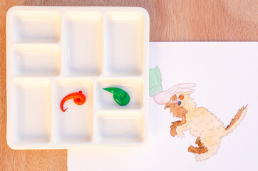 watercolor painting in progress with green and red paint and cartoon style cat drawing on white paper