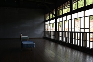 古い窓ガラスに囲まれた古民家の大広間に設置されている椅子