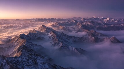 Aerial view of snow-capped mountain peaks rising above a sea of clouds at sunrise