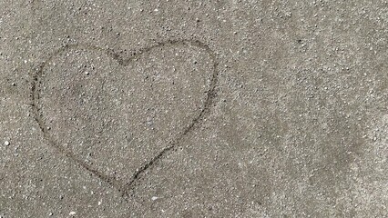 Heart shape drawn in sand on a beach, surrounded by fine grains, showcasing a romantic gesture and connection to nature, perfect for love-themed projects and designs