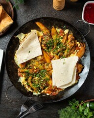 Savory dish of spiced potatoes and grilled meat served with fresh herbs and flatbread in a rustic dining setting