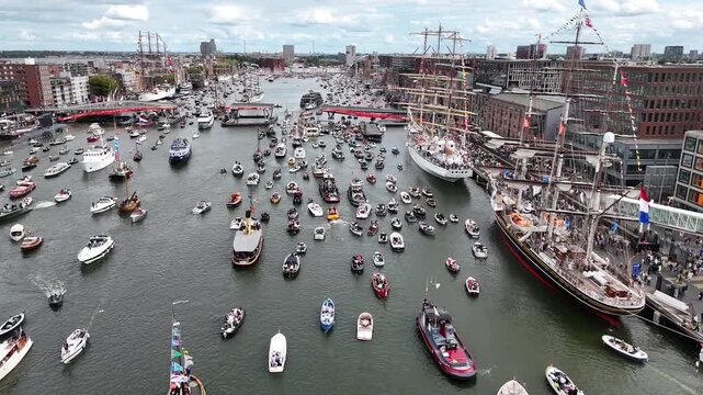 Amsterdam, Netherlands 23 August 2025: Drone footage of Sail 2025 - Sailing Parade in Amsterdam. Enjoy the view of the sail boats by the docks and in the canals of Amsterdam from a Birds Eye view