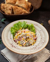 Delicious salad with corn served on a rustic table alongside freshly baked bread