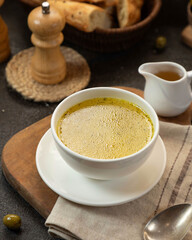 Delicious warm soup served in a white bowl with bread on a rustic wooden table in a cozy kitchen setting