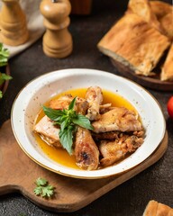 Delicious chicken dish with herbs served alongside warm bread on a rustic wooden table