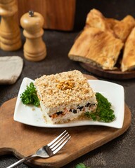 Delicious layered salad with creamy filling served on a wooden table with bread in a rustic setting