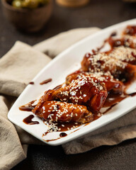 Delicious baked chicken wings with sesame seeds, served on a white platter for an appetizing meal experience