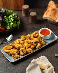 Delicious fried mushrooms served with dipping sauce, fresh herbs, and bread in a cozy kitchen setting