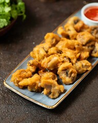 Crispy vegetable fritters served with spicy dipping sauce at a vibrant market stall