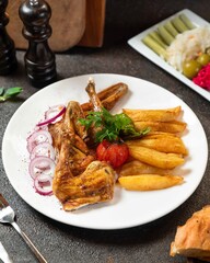 Delicious grilled chicken with crispy fries served alongside fresh vegetables and herbs in a cozy dining setting