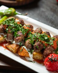Delicious grilled meatballs served on crispy potatoes with fresh herbs and red sauce in a cozy restaurant setting