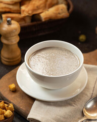 Delicious bowl of creamy mushroom soup with crunchy croutons and bread on the table