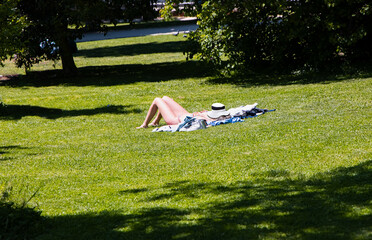 Blonde woman sunbathing on the grass wearing a white bikini - El Retiro park, Madrid, Spain