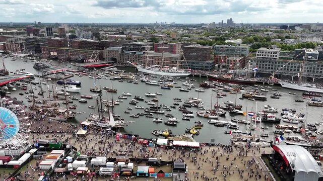 Amsterdam, Netherlands 23 August 2025: Drone footage of Sail 2025 - Sailing Parade in Amsterdam. Enjoy the view of the sail boats by the docks and in the canals of Amsterdam from a Birds Eye view