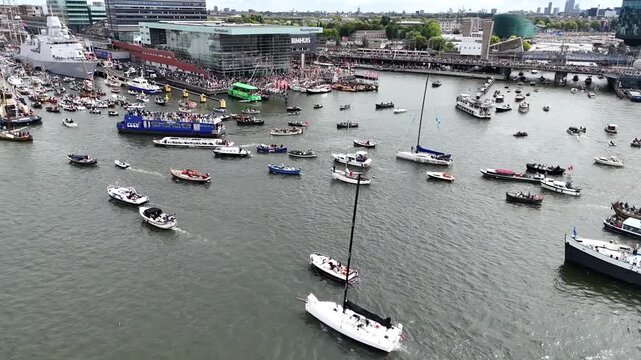 Amsterdam, Netherlands 23 August 2025: Drone footage of Sail 2025 - Sailing Parade in Amsterdam. Enjoy the view of the sail boats by the docks and in the canals of Amsterdam from a Birds Eye view