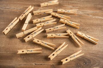 Wooden clothespins scattered on a rustic wooden table during daylight, showcasing their natural color and texture