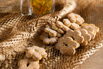 Delicate flower-shaped cookies served alongside a warm cup of herbal tea on a woven mat