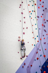 The girl climbs the climbing wall.