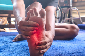 Foot pain, Asian man feeling pain in his feet at home, Man suffering from foot pain using hand...