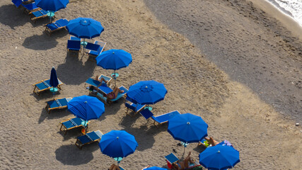 Aerial view of a beach resort with blue umbrellas. People on vacation are sunbathing. Holiday concept.