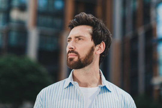Confident young man in casual attire standing in an urban area on a sunny day, showcasing modern lifestyle.