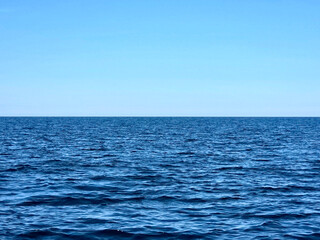 An expansive view of Lake Michigan stretches out to meet a clear blue sky