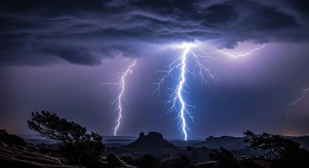 Fototapeta premium Dramatic Lightning Storm Over Mountainous Landscape with Dark Clouds and Silhouetted Trees